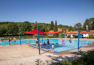Outdoor swimming pool at Camping Walsheim, Saarland, Germany, with children and adults enjoying sunny weather.