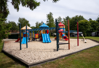 Parco giochi con scivoli colorati e altalene su sabbia al Camping de Zeven Heuveltjes, Drenthe, Paesi Bassi.