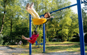 Due bambini giocano sulle altalene nel parco giochi soleggiato di Camping de Zeven Heuveltjes, Drenthe, Paesi Bassi.