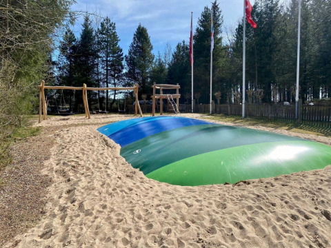 Grande cuscino gonfiabile per saltare e altalene nell’area giochi di Tolne Camping, Jutland del Nord, Danimarca.