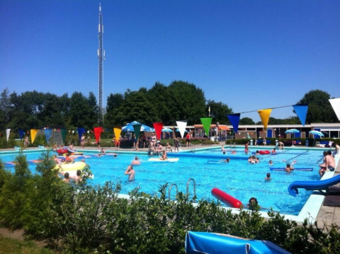 Outdoor swimming pool filled with people at Camping Tussen de Diepen holiday park, Overijssel, Netherlands.