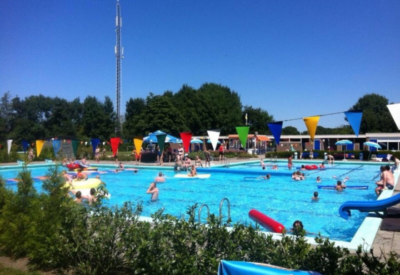 Piscina all'aperto affollata al Camping Tussen de Diepen, parco vacanze a Overijssel, Paesi Bassi.