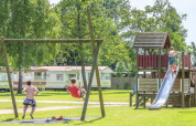 Bambini che giocano su altalene e scivolo al Camping Tussen de Diepen, Overijssel, Paesi Bassi.
