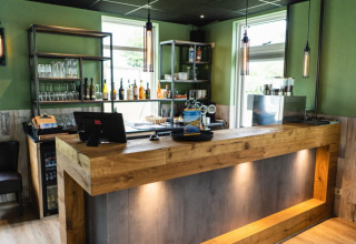 Moderne bar med trædisk, hylder med glas og flasker, ved Camping Tussen de Diepen i Overijssel, Holland.