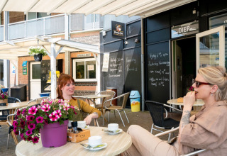 Deux femmes prennent un café en terrasse au Camping Tussen de Diepen, un parc de vacances aux Pays-Bas.
