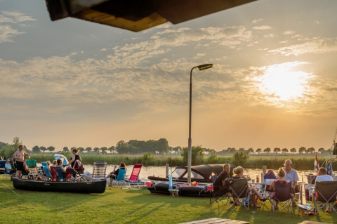 Des personnes se détendent au bord de l’eau au Camping Tussen de Diepen à Overijssel, Pays-Bas, au coucher du soleil.