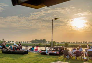 Des personnes se détendent au bord de l’eau au Camping Tussen de Diepen à Overijssel, Pays-Bas, au coucher du soleil.