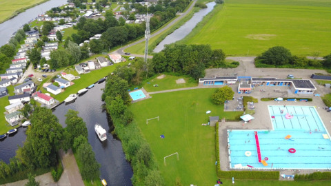 Luftaufnahme vom Camping Tussen de Diepen mit Pool, Wiesen und Booten im niederländischen Overijssel.