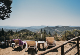 Scenic view from Camping Luna del Monte in Umbria, Italy, with loungers overlooking rolling green hills.