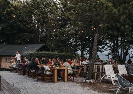 Buiten samen eten onder lichtjes en bomen bij Camping Luna del Monte, een vakantiepark in Umbrië, Italië.