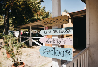 Cartelli di legno colorati per reception, bar della piscina, gelato e piscina a Camping Luna del Monte, Umbria, Italia.