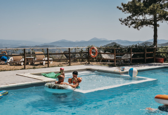 Famiglie che si rilassano in piscina con vista sulle colline al Camping Luna del Monte in Umbria, Italia.