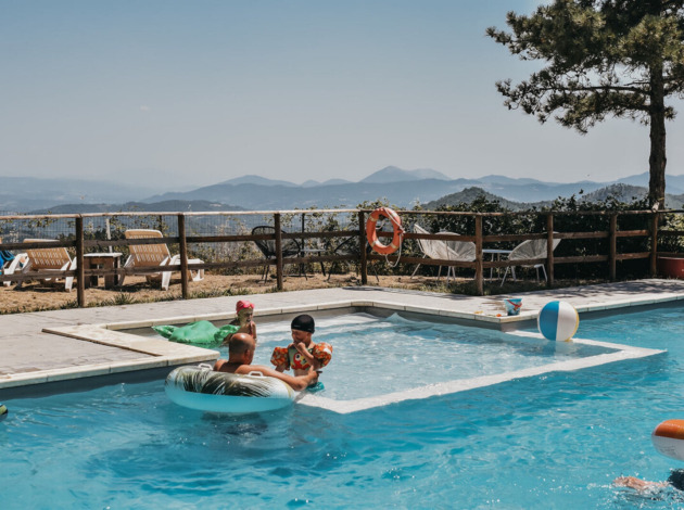 Gezinnen genieten van een zwembad met prachtig uitzicht bij Camping Luna del Monte in Umbrië, Italië.