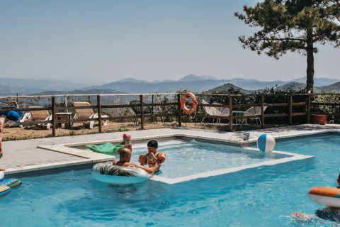 Famiglie che si rilassano in piscina con vista sulle colline al Camping Luna del Monte in Umbria, Italia.