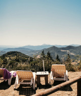 Sun loungers facing scenic hills at Camping Luna del Monte holiday park in Umbria, Italy, on a clear day.
