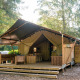 Safari telt med veranda og eget bad, omgivet af træer, perfekt til komfortabel camping i naturen.