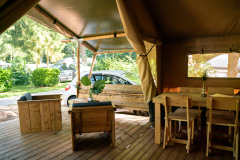 Interieur van een safaritent met houten meubelen en uitzicht bij Camping de Zeven Heuveltjes in Nederland.