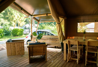 Interior de una tienda safari con muebles de madera y vistas exteriores en Camping de Zeven Heuveltjes, Países Bajos.