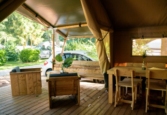 Interior de una tienda safari con muebles de madera y vistas exteriores en Camping de Zeven Heuveltjes, Países Bajos.
