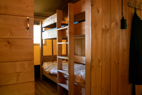 Interieur van safaritent met houten stapelbed en wanden bij Camping de Zeven Heuveltjes, Nederland.