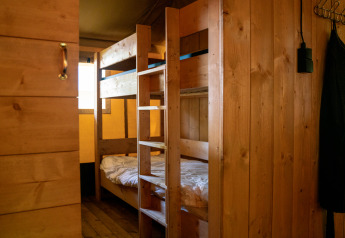 Interior de tienda safari con litera de madera y paredes de madera en Camping de Zeven Heuveltjes, Países Bajos.