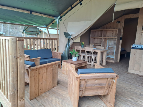 Safari tent with wooden furniture and covered deck at Camping de Zeven Heuveltjes in the Netherlands.