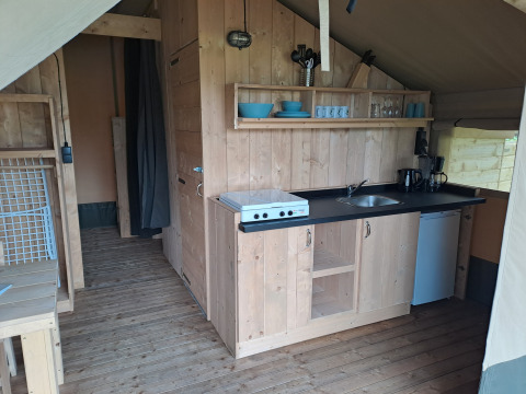 Keukenhoek in een safaritent met fornuis, spoelbak en koelkast bij Camping de Zeven Heuveltjes in Nederland.