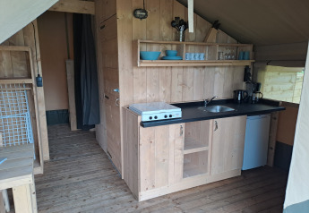 Køkkenområde i safaritelten med komfur, vask, køleskab og træindretning på Camping de Zeven Heuveltjes.