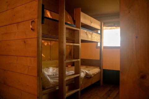 Binnenaanzicht van een safaritent met houten stapelbedden op Camping de Zeven Heuveltjes in Nederland.