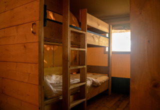 Binnenzicht van een safaritent met houten stapelbedden bij Camping de Zeven Heuveltjes in Nederland.