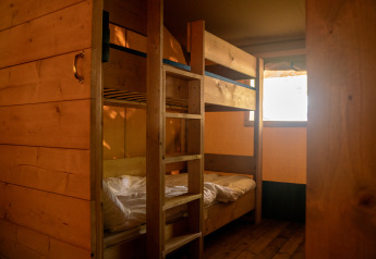 Binnenaanzicht van een safaritent met houten stapelbedden op Camping de Zeven Heuveltjes in Nederland.