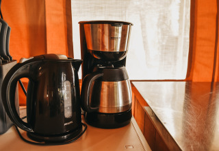 Macchina del caffè e bollitore elettrico su un piano cucina in tenda safari al Camping Luna del Monte, Italia.