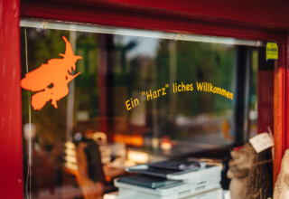 Ingang van Camping Braunlage met Duits welkomstbord en heksfiguur in Nedersaksen, Duitsland.