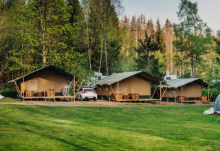 Tentes de luxe au Camping Braunlage en Basse-Saxe, Allemagne, entourées de gazon et de forêt verdoyante.