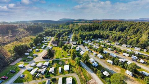 Vista aérea del Camping Braunlage en Baja Sajonia, Alemania, rodeado de caravanas y un entorno boscoso verde.