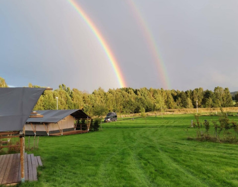 Doble arcoíris sobre campos verdes y tiendas en Camping de Regenboog, Ústí nad Labem, República Checa.