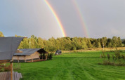 Doppio arcobaleno sopra i campi verdi e tende al Camping de Regenboog, Ústí nad Labem, Repubblica Ceca.
