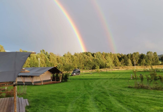 Dubbele regenboog boven groene velden en tenten bij Camping de Regenboog, Ústí nad Labem, Tsjechië.