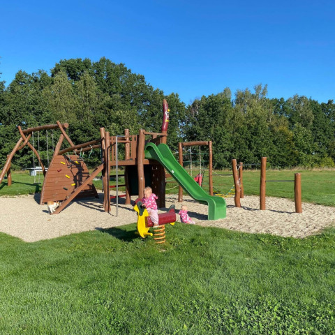 Niños juegan en un parque infantil con tobogán y balancín en Camping de Regenboog, Ústí nad Labem, República Checa.