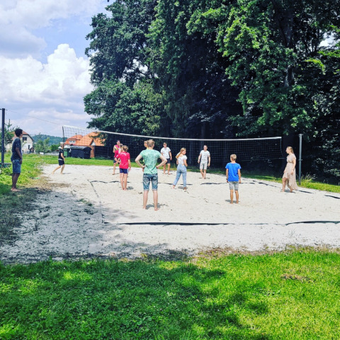 Bambini e adulti giocano a pallavolo su un campo di sabbia a Camping de Regenboog, Ústí nad Labem.