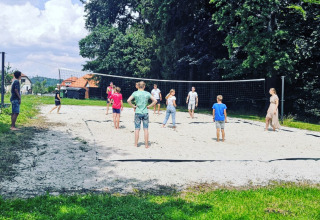 Børn og voksne spiller volleyball på en sandbane i Camping de Regenboog, Ústí nad Labem, Tjekkiet.