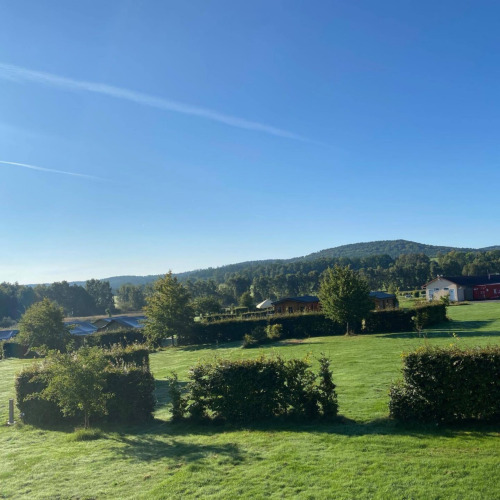 Sonnige Landschaft mit grünen Wiesen, Hecken, Bäumen und Hütten im Camping de Regenboog, Ústí nad Labem.