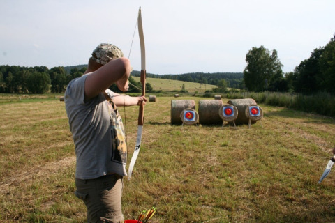Person practicing archery and aiming at targets on hay bales in a field at Ústí nad Labem, Czech Republic.