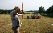 Person practicing archery and aiming at targets on hay bales in a field at Ústí nad Labem, Czech Republic.