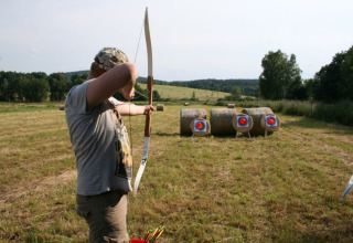 Person practicing archery and aiming at targets on hay bales in a field at Ústí nad Labem, Czech Republic.