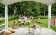 Famiglia si gode il tempo sulla veranda del Veranda chalet con giardino a Camping Sevink Molen.