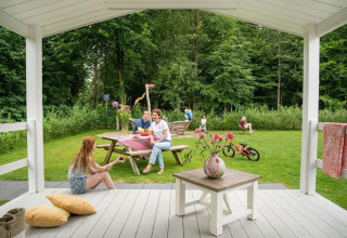Gezin geniet op het terras van het Veranda chalet met tuin bij Camping Sevink Molen in Nederland.
