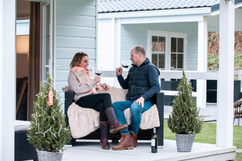 Couple enjoying wine on the veranda at Veranda chalet with hot tub at Camping Sevink Molen, Netherlands.