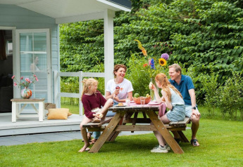 Gezin eet samen buiten bij Veranda chalet met hot tub bij Camping Sevink Molen in Nederland.