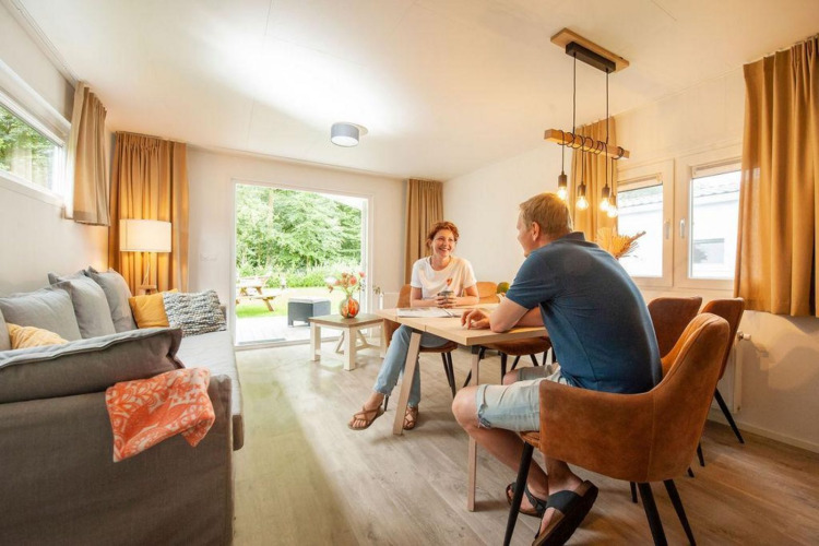 Una pareja charla en una cabaña luminosa y acogedora en Camping Sevink Molen, Países Bajos, junto a la mesa.